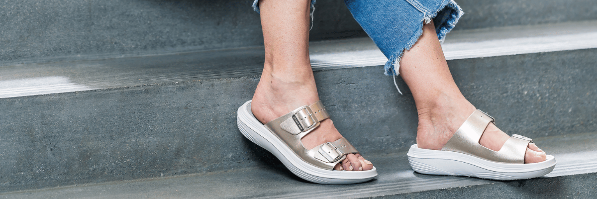 women wearing gold sandals on grey background