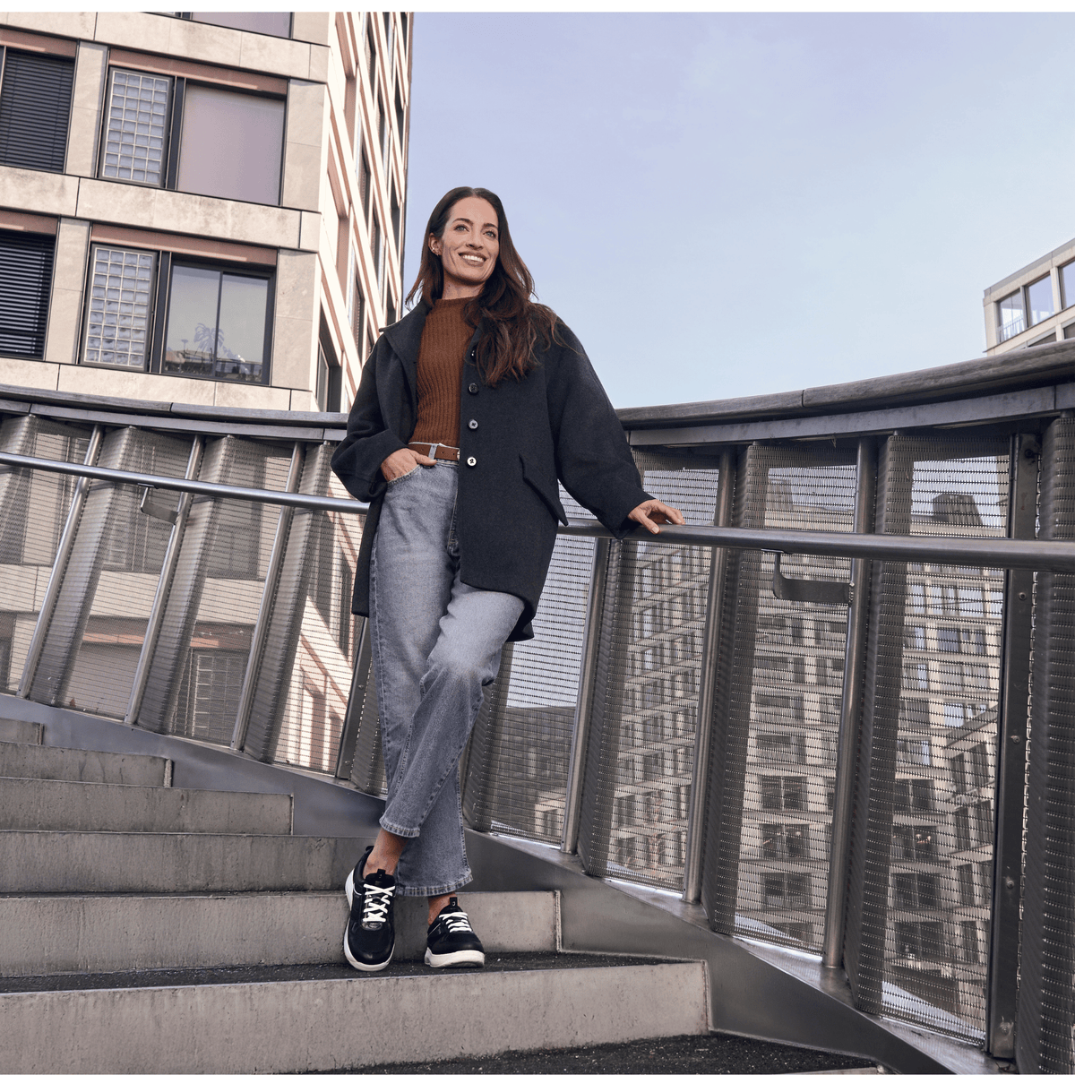 women standing on stairs outside with metal railing wearing blue jeans and black and white sneakers.