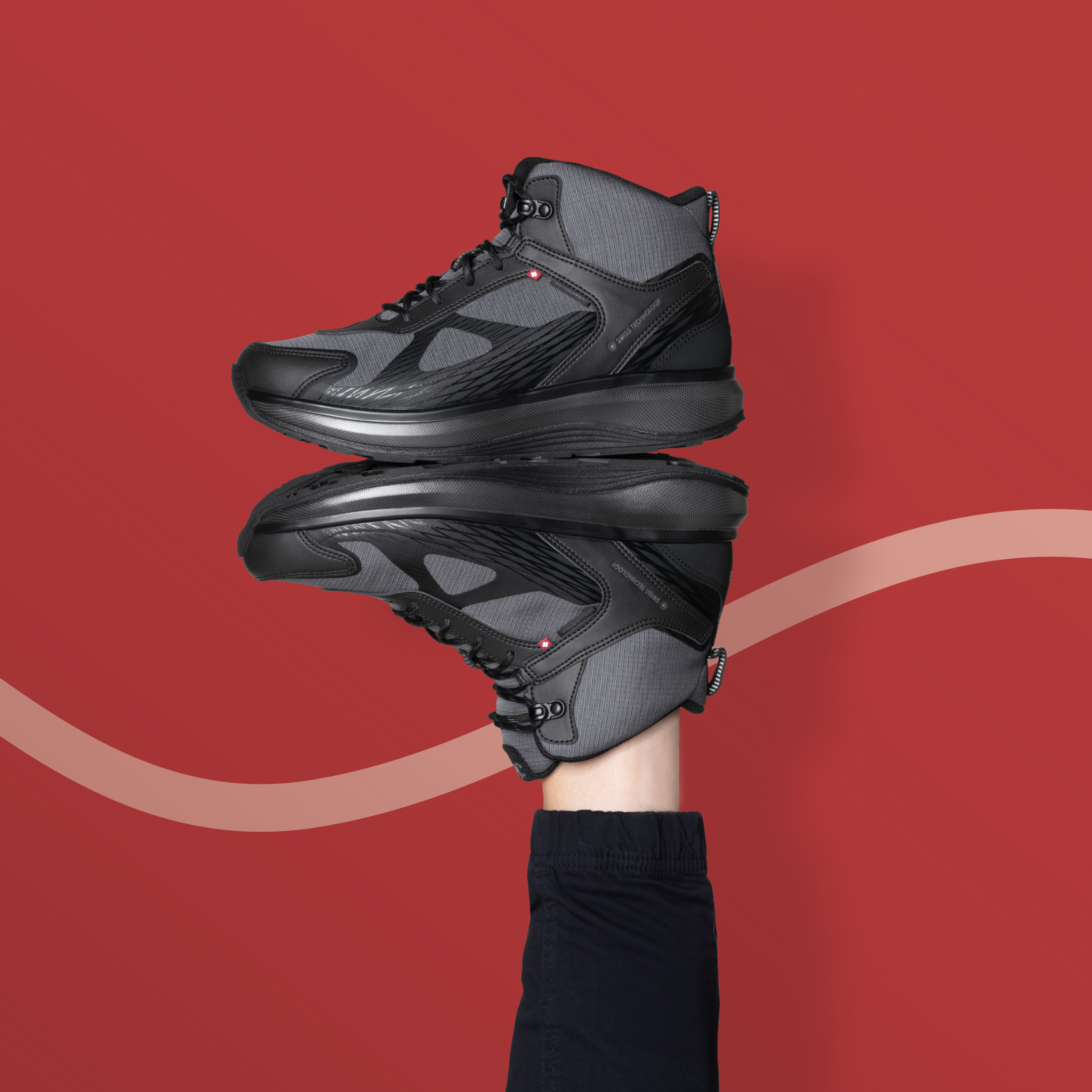 Black high-top sneakers stacked on top of each other with a red background