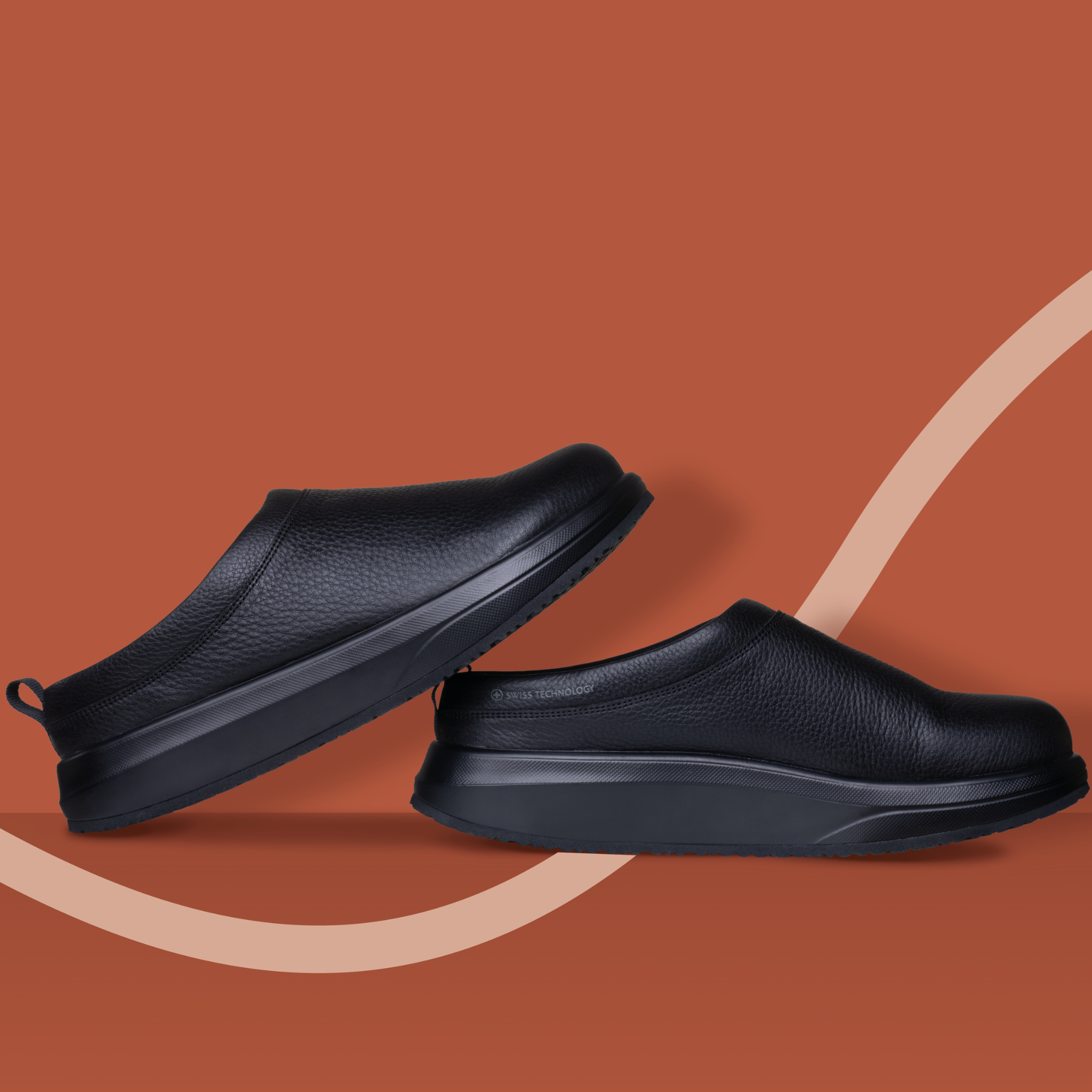 Pair of black slip-on shoes on a brown background