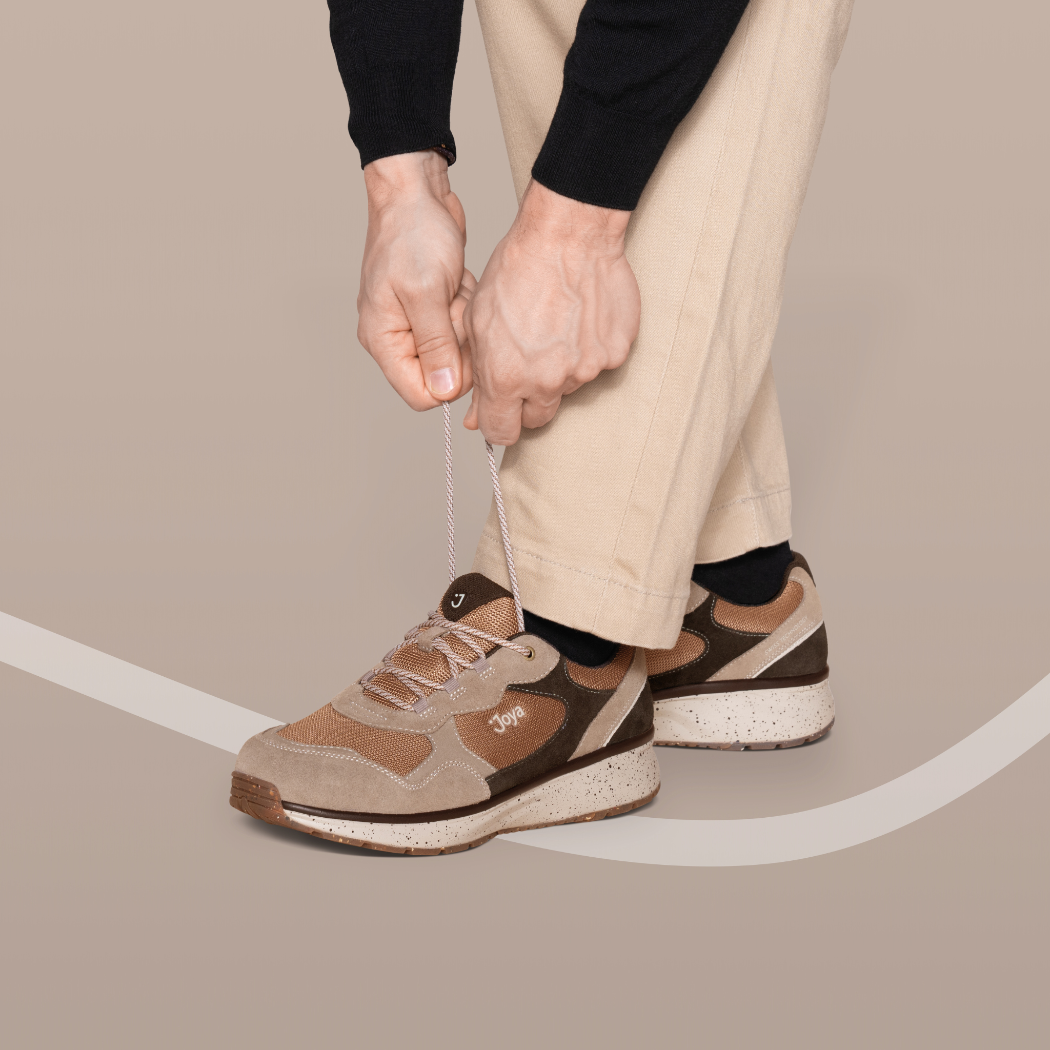 Person tying shoelaces on brown sneakers with a neutral background