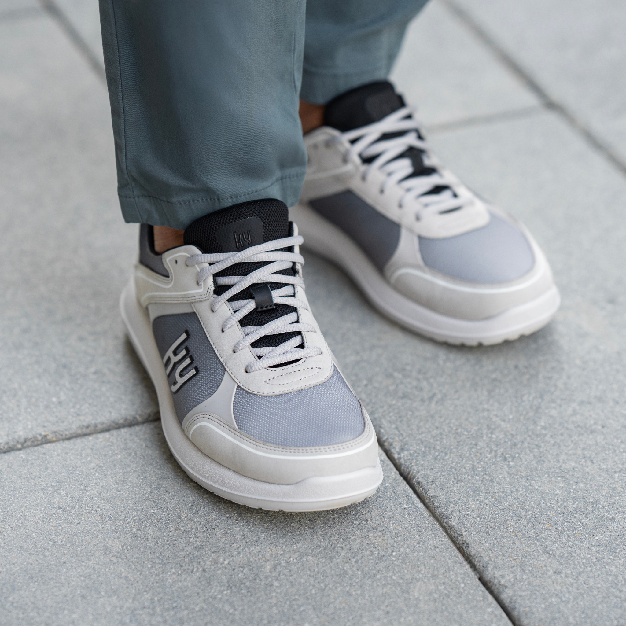 man wearing light grey shoe on grey stone background