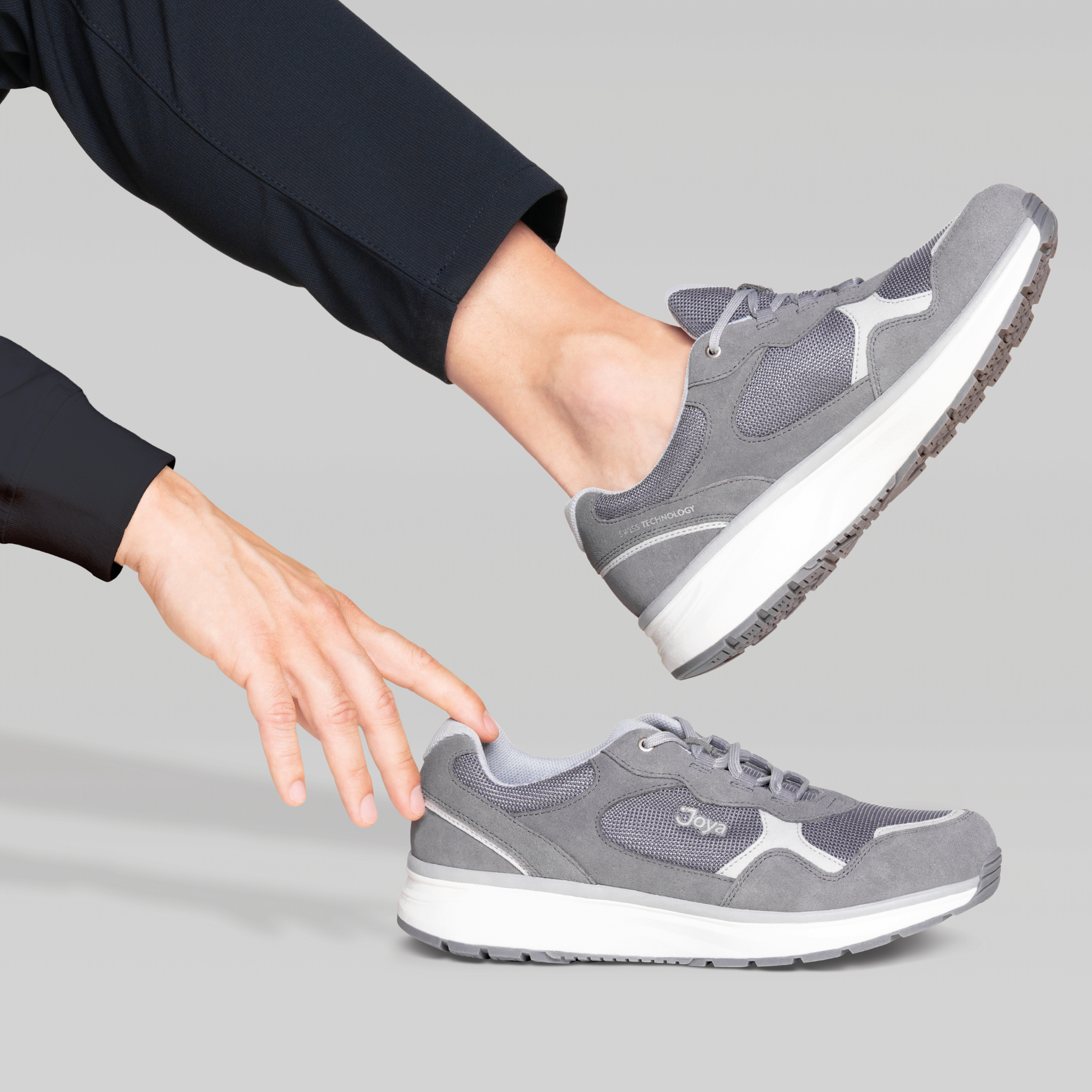 hand reaching for grey sneaker on grey background