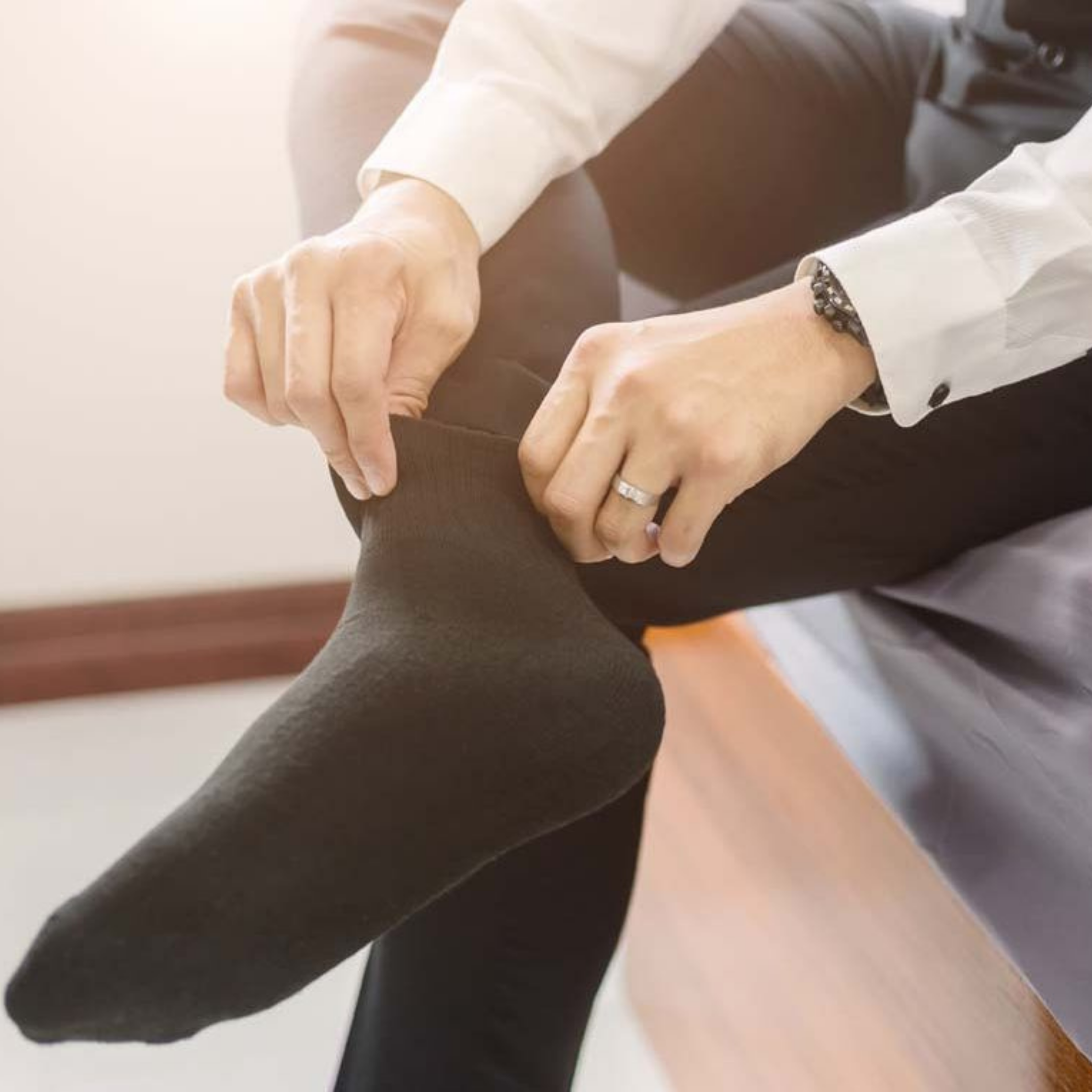Person wearing black socks and a white shirt, sitting on a couch.