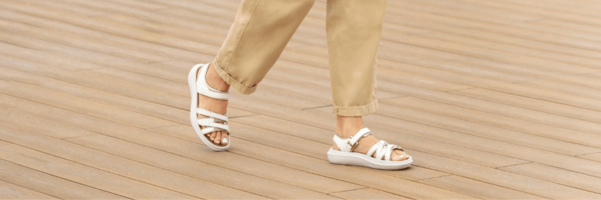 women walking on light brown wooden surface in white kybun sandals