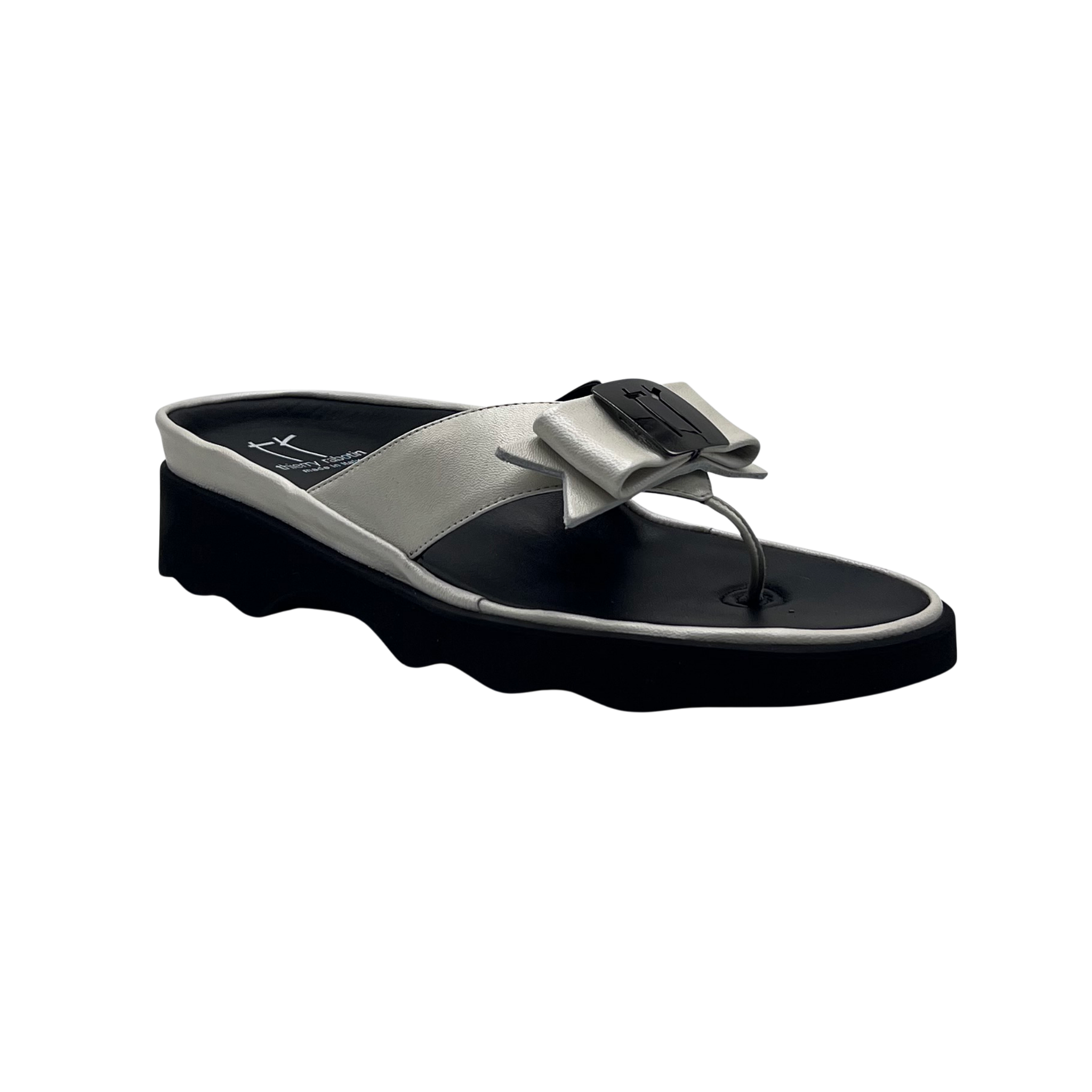 A single women's thong sandal with a chunky black platform sole, a light gray strap, and a large decorative bow on the toe strap, shown against a plain white background.
