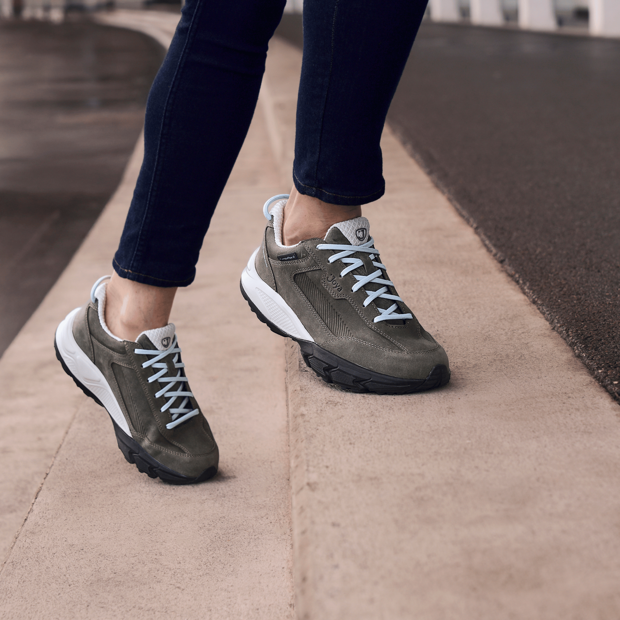 women wearing black jeans and dark grey suede sneakers on beige steps