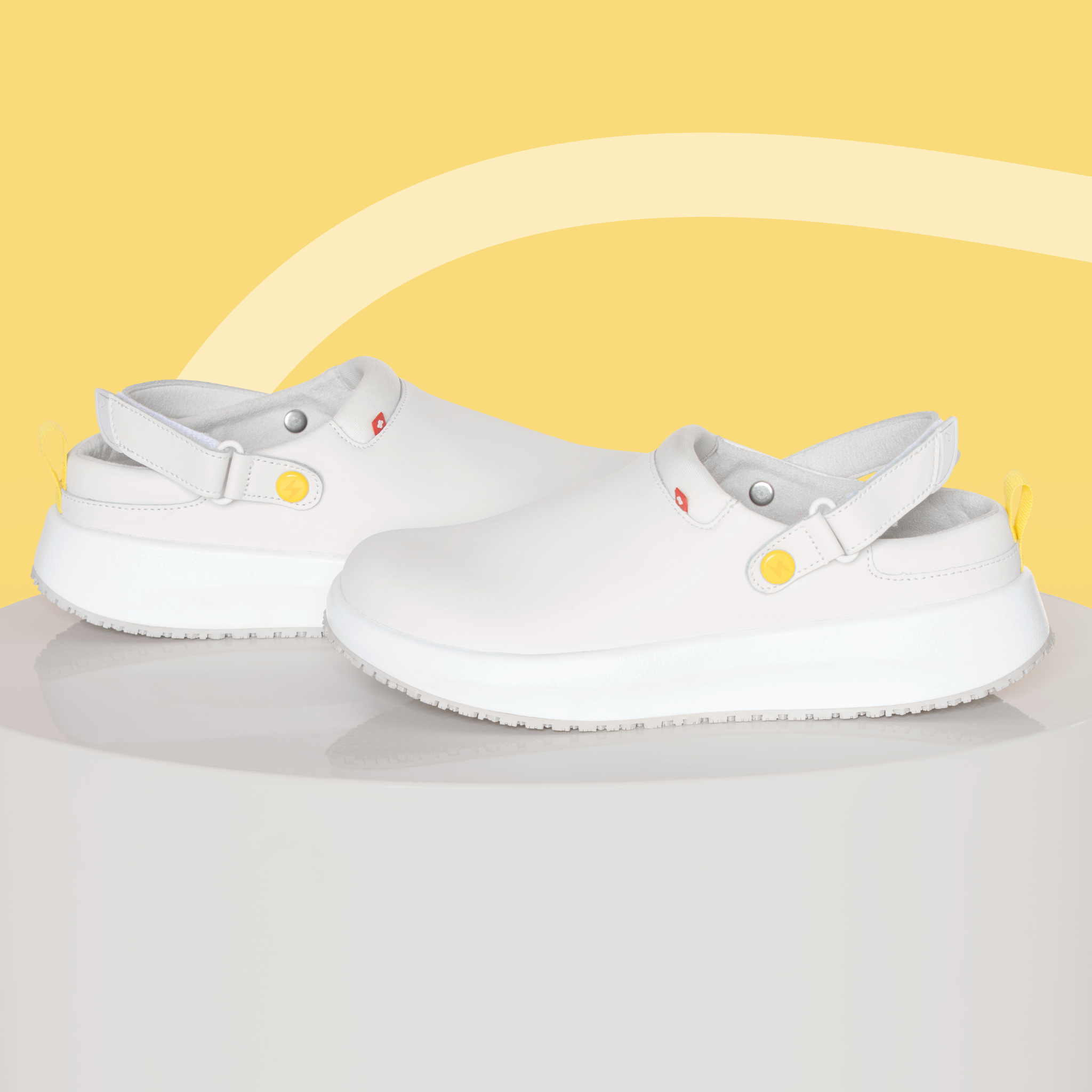 White clogs with yellow accents on a light gray surface with a yellow background