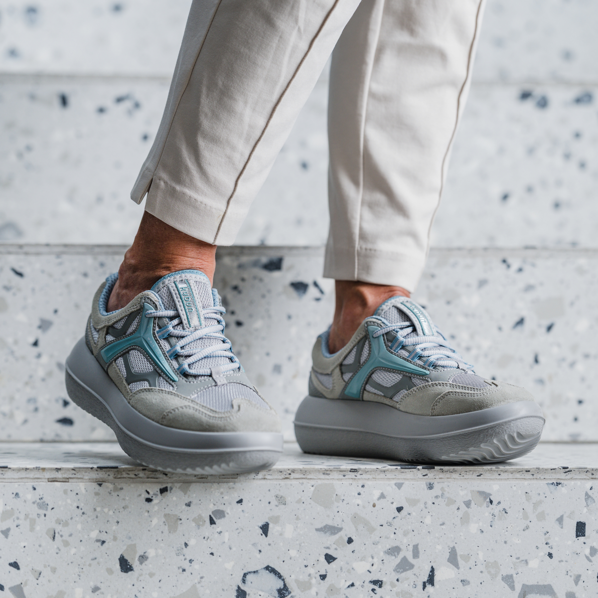 close up of grey shoes with blue trim standing on marble stairs