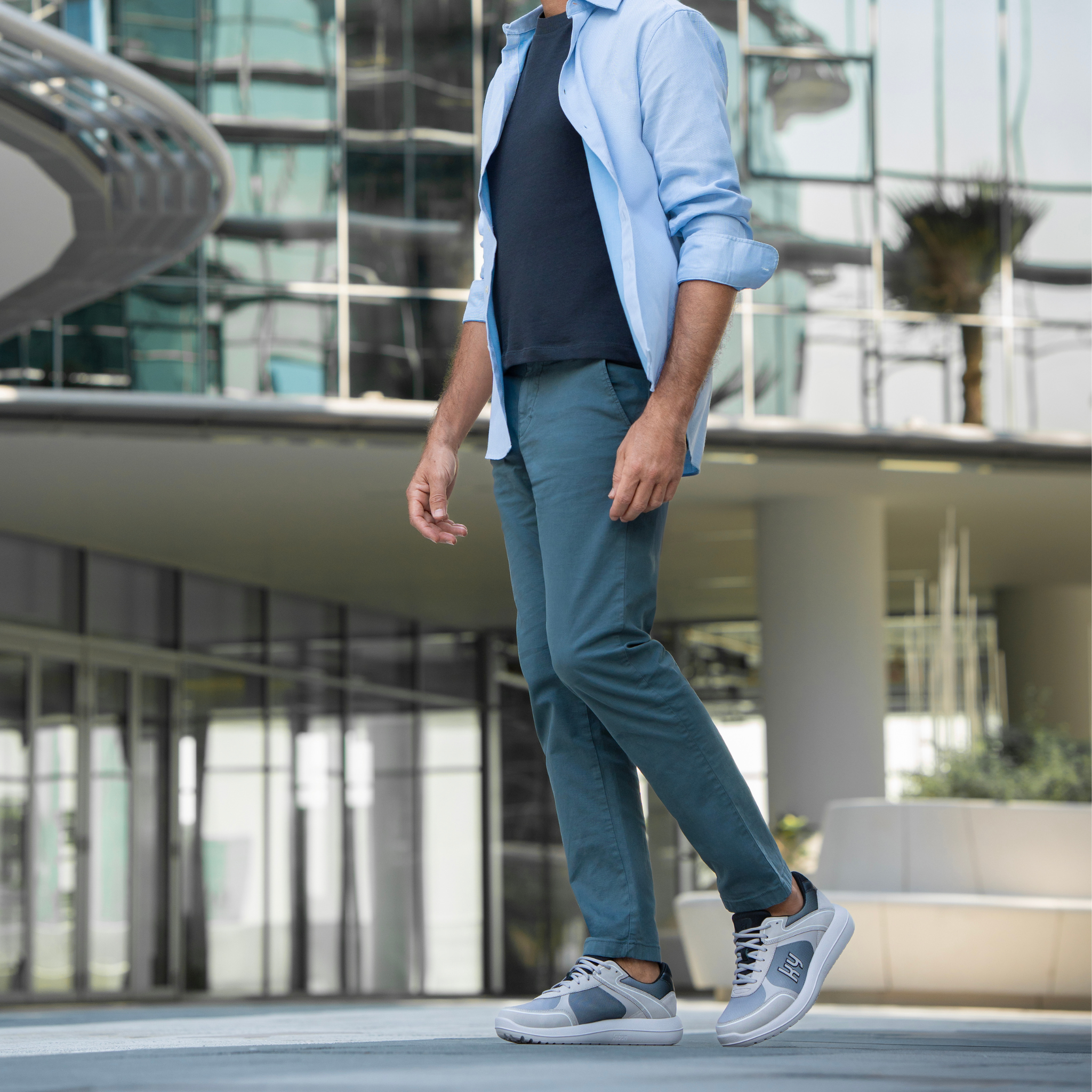 man in a street scene wearing blue shirt and light grey shoes