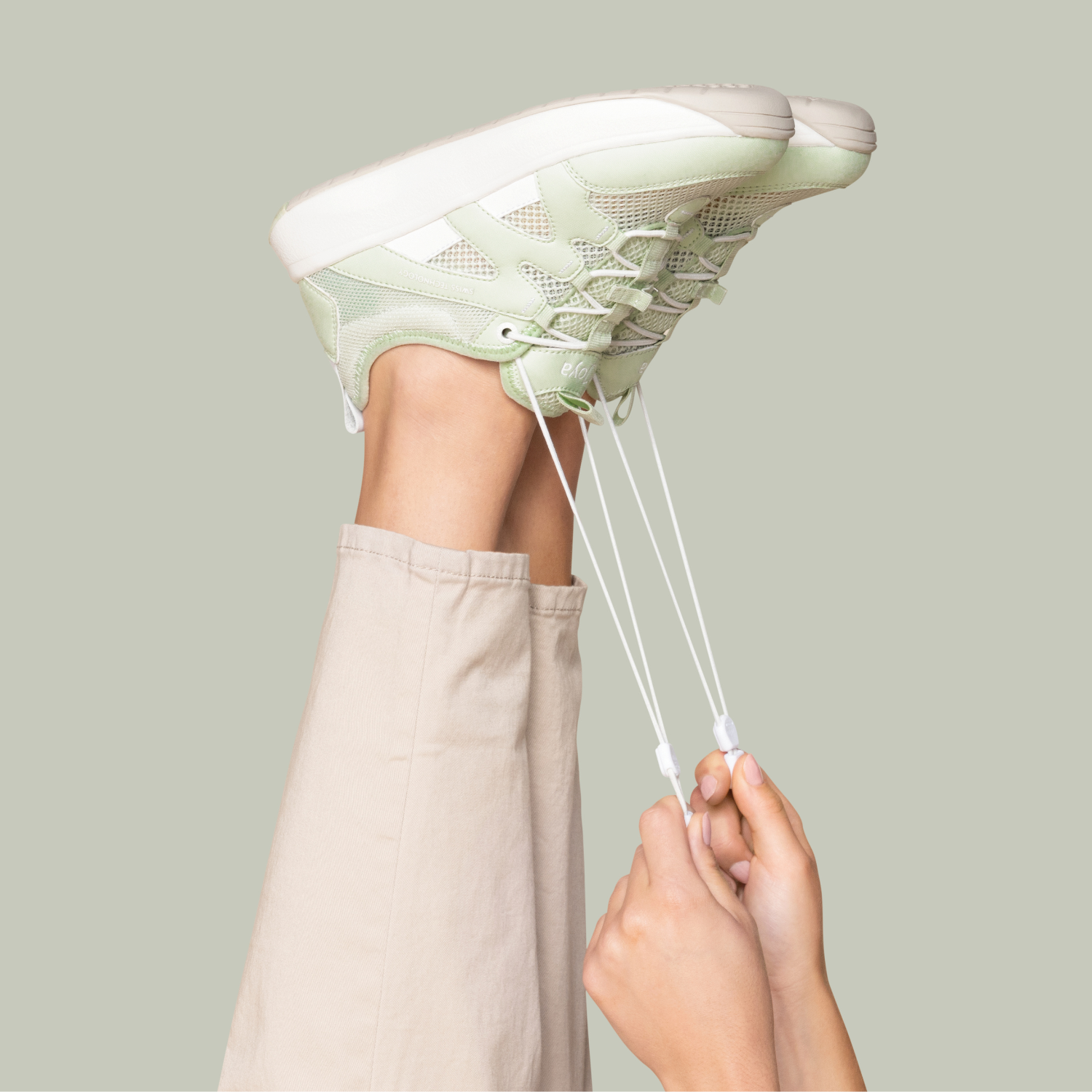 Person wearing a light green sneaker with a neutral background