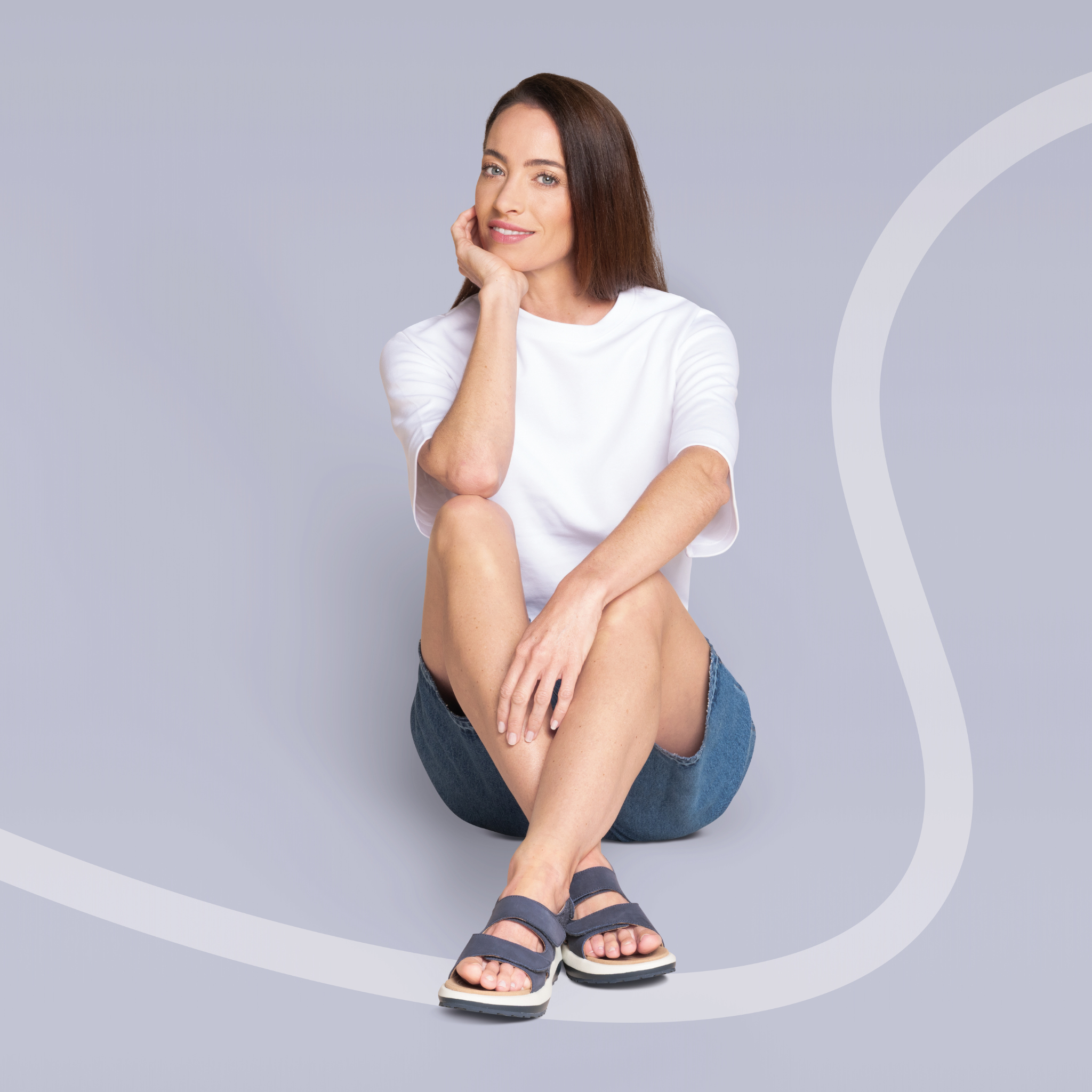 women sitting down on blue background wearing sandals