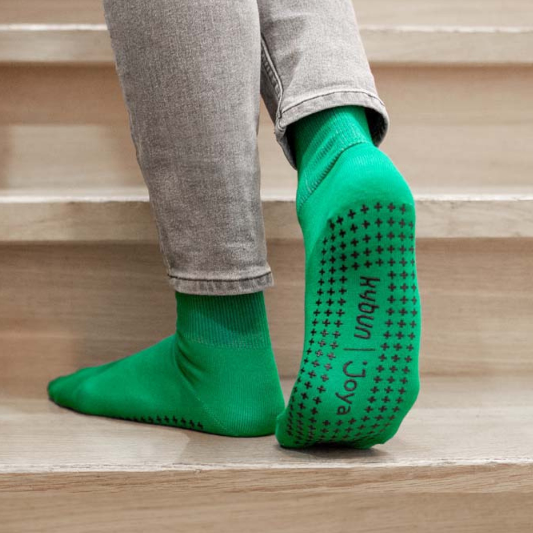 person wearing green grip socks on wood background 